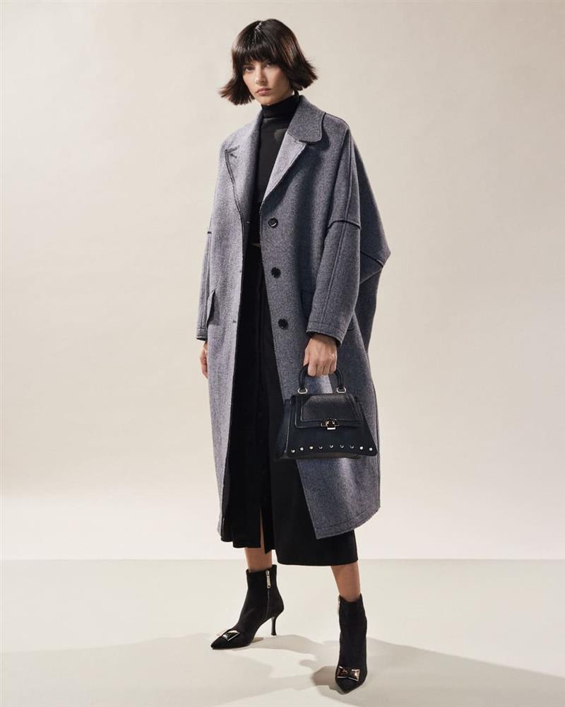 femeie bruneta imbracata cu rochie neagra,  palton si botine negre din piele